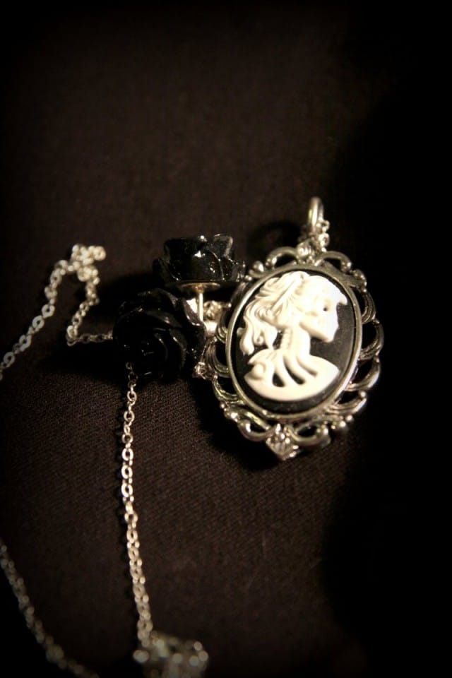 Pääkallonaisen siluetti medaljongissa ja mustat ruusukorvikset -setti