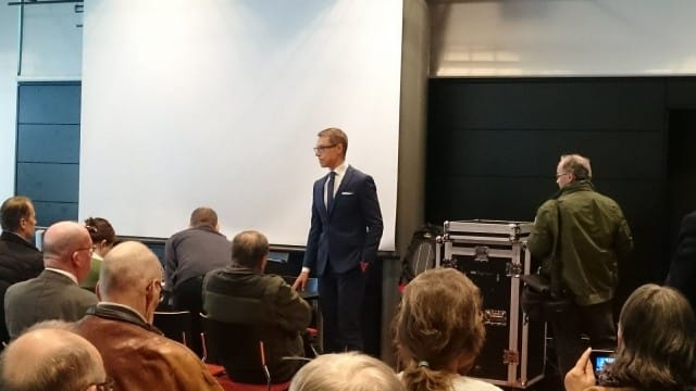 Alexander Stubb pitää vaalitilaisuutta ja samalla TesPack -aurinkoenergialaukun fani nosti tuotesijoittelulla (ilman lupaa??) tuotteen kuviin.