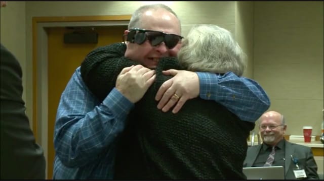 Allen Zderad syleilee vaimoaan bioniset silmälasit päässään.