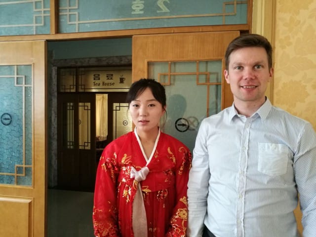 Korealainen tarjoilija juhlapuvussa ja seikkailija Ilkka Lavas.