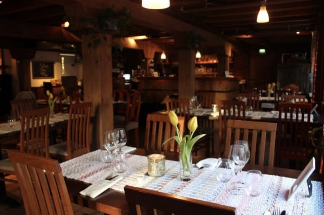 Ruokailutilojen hirsipalkit muistuttavat rakennuksen historiasta. Pöytien kaitaliinat on kudottu Finlaysonin ylijäämätekstiileistä, ja ne luovat ravintolaan rentoa hygge-tunnelmaa.