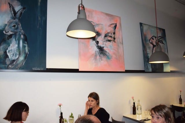 Seiniä kiertävät Nora Helsingin maalaukset.