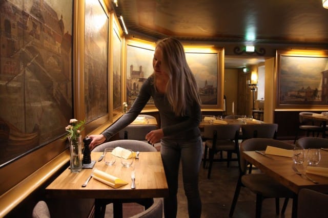 Teinin ruokasalista ei lopu katseltava: seiniä peittävät taulut ja kattoa maalaukset. Mindi Väätäinen valmistelee pöydät lounaskuntoon.