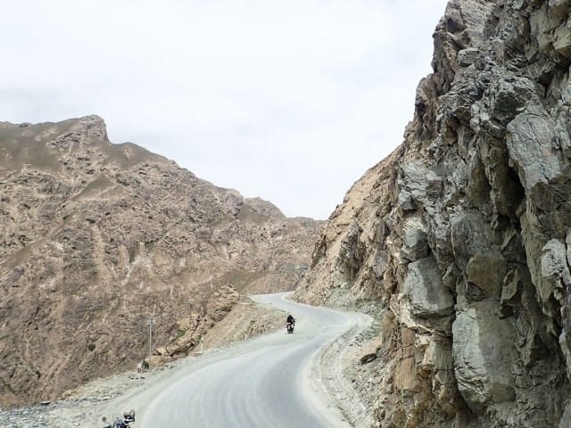 Moottoripyörällä Kiinassa Tiibetin ja Xingiangin rajalla. Oikealla nousee vuori, vasemmalla aukeaa yli kilometrin syvä rotko.