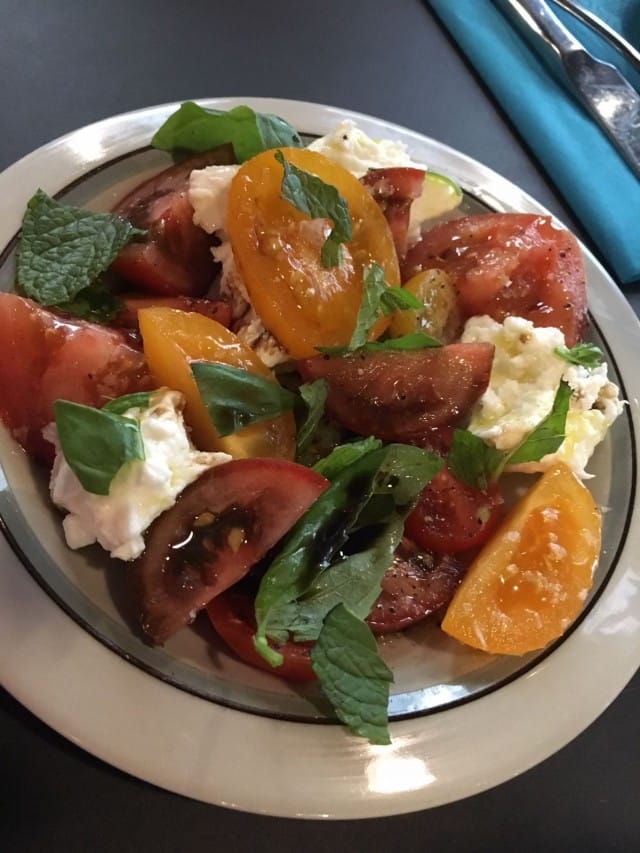 Raikas Caprese-salaatti, jonka kruunaa Mozzarella di Bufala -juusto ja tuore basilika.