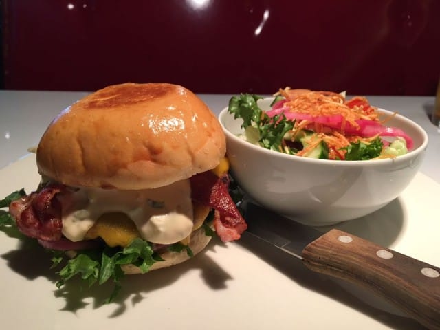 Herkullinen American Cheese -burgeri pekonilla ja lisukesalaatilla.