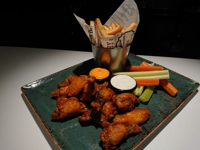 Hiilen friteeratut wingsit tarjoillaan rapeiden maalaisranskalaisten ja dippien kera.