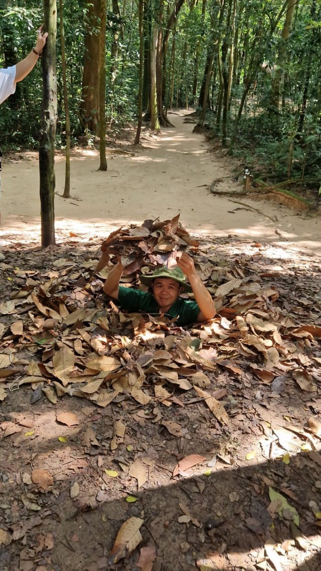 Vietnamilainen opas näyttää Cu Chissa miten tunneliin mennään.