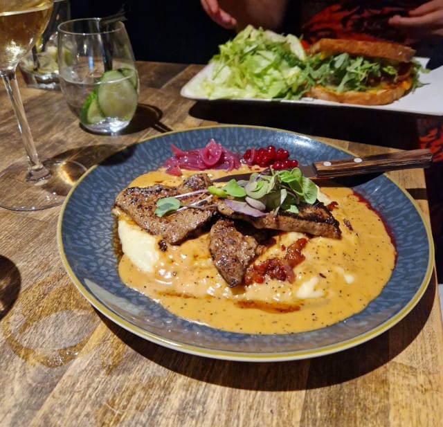 Paistettua naudanmaksaa, perunamuusia, kermaista jaloviinalla maustettua pekonikastiketta, puolukkasurvosta ja sipulihilloketta.