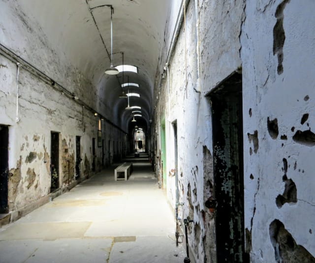 Vankilan rapautunut käytävä, joka on puolittain hämärä. 