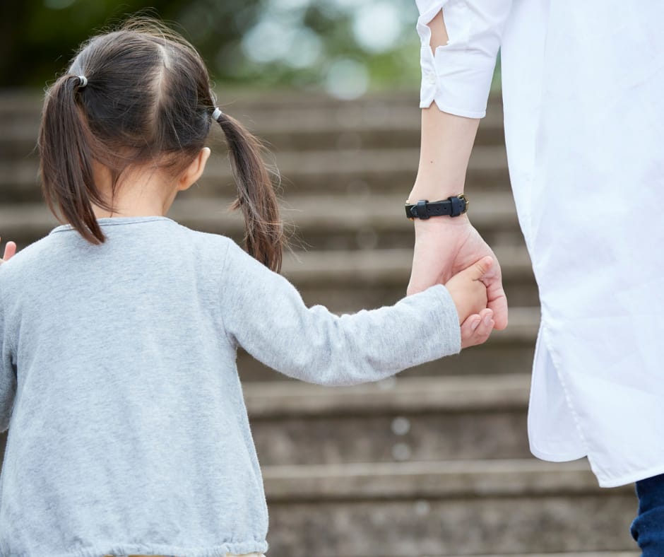 Kuvassa näkyy lapsi ja hänen vanhempi takaa päin. Lapsella on saparot päässään.