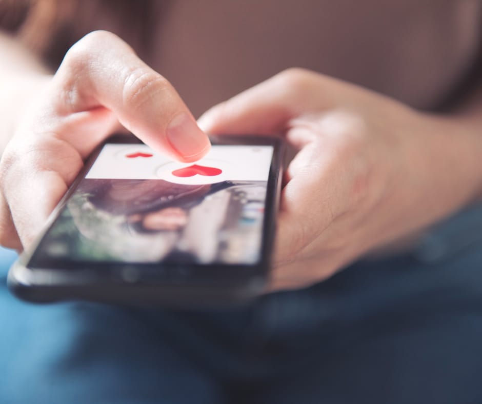 Kuvassa henkilö on tykännyt jonkun treffiprofiilista. Kuvassa näkyy naisen kädet ja kännykkä, jossa on miehen kuva ja tykkäys.