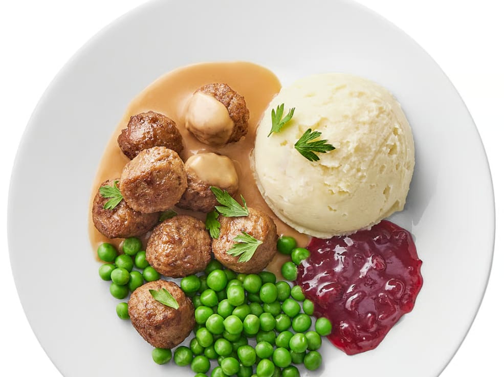 Annos Ikean lihapullia, kastiketta, puolukkahilloa ja herneitä lautasella.