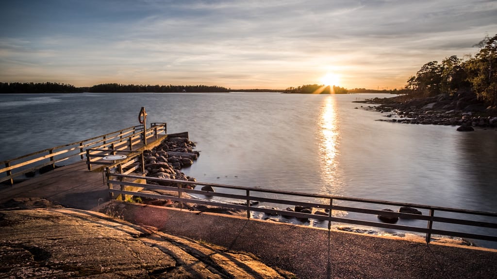 Kesäinen auringonlaskunäkymä, laituri ja merta Lauttasaaressa.