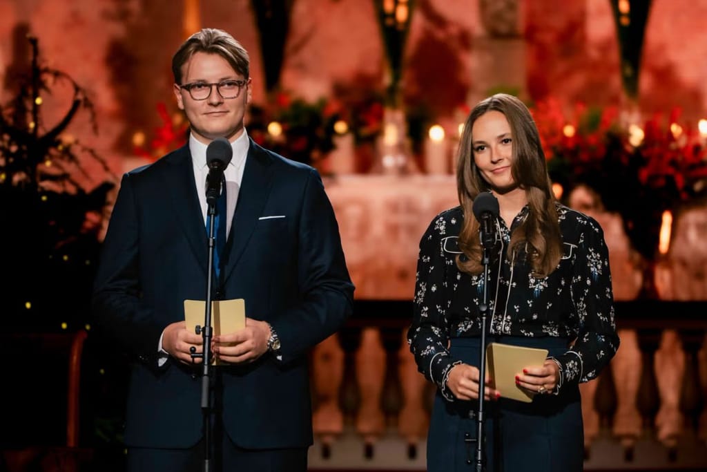 Norjan kruununperijät Ingrid Alexandra ja Sverre Magnus, jotka pitivät puheet tilaisuudessa. Kuvassa punaista taustaa vasten ja molemmat seisovat mikrofonien edessä joulutilaisuudessa. 