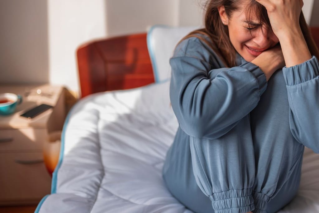 Nainen itkee sängyllä. Kuvituskuva. 