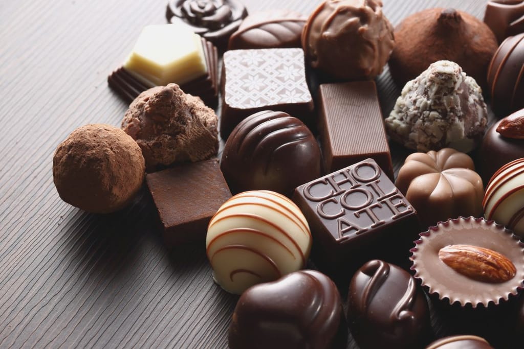 Konvehtisuklaita, sekä tummia, että vaaleita ja osassa pähkinää ja vuoka mukana. Kuvituskuva. 