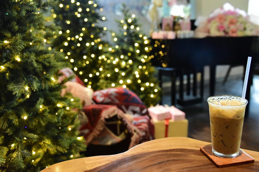 Jouluinen olohuone, jossa iso koristeltu joulukuusi, pöytä jonka reunalla on makukahvi ja lattialla lahjapaketteja. 