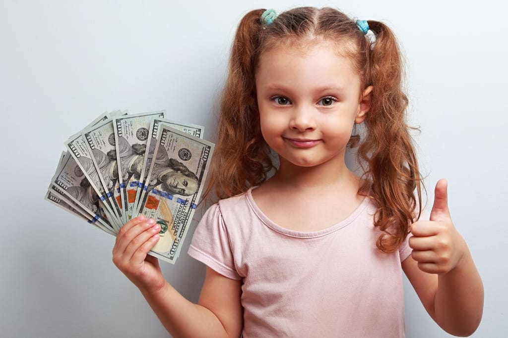 pikku tyttö pitelee setelitukkoa ja näyttää peukaloa