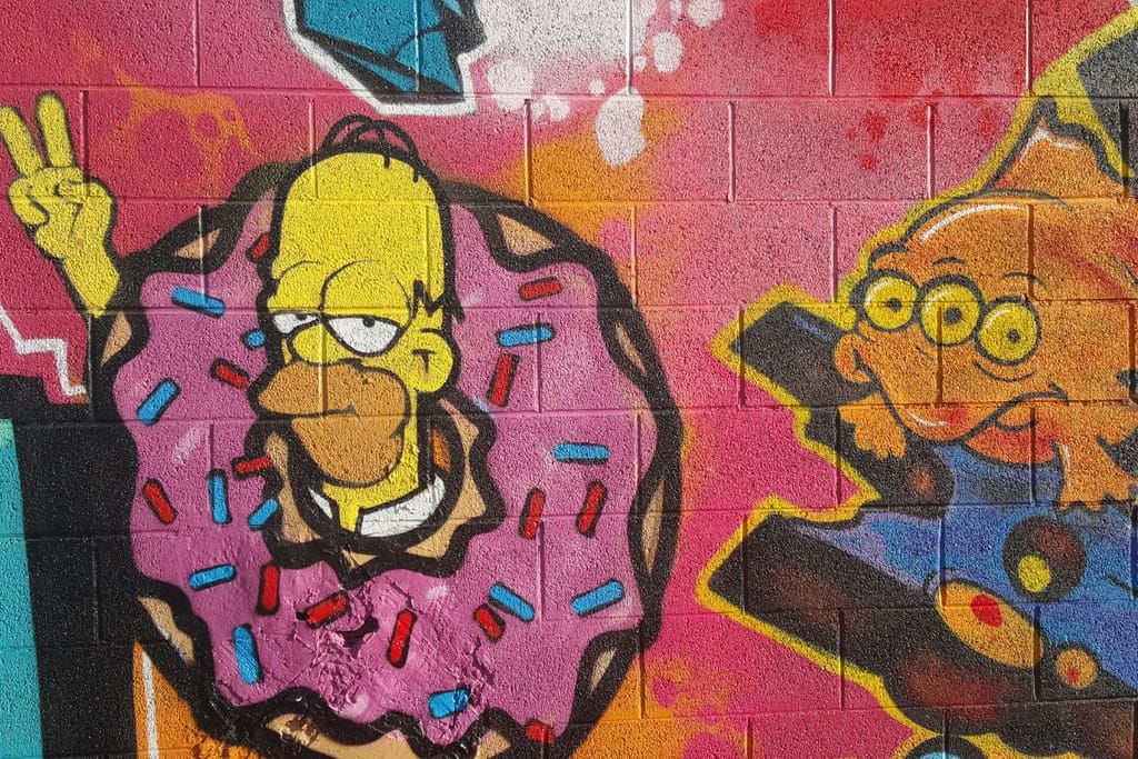 Homer Simpson donitsiin käärittynä kolmisilmäisen kalan kanssa sarjasta The Simpsons. Katutaidetta Saksasta, spraymaalaus. 