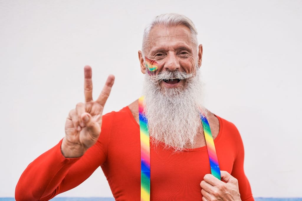 Sateenkaaritunnuksiin pukeutunut mies, jolla on pukin parta ja henkselit. Kuvituskuva LGBT artikkeliin. 