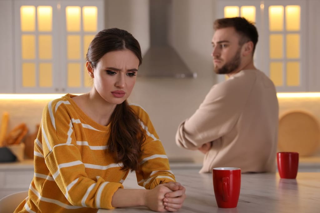 Nainen ja mies kahvikuppien kanssa pöydän ääressä. Selkeästi jonkinlainen riitatilanne menossa, ja kuvituskuvana artikkeliin joka käsittelee mustasukkaisuutta. Naisella on raidallinen keltavalkoinen paita, kupit punaisia ja miehellä parta. 