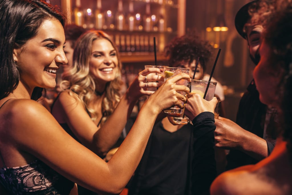Joukko naisia sanoo kippis drinkit kädessä ja skoolaavat juhlallisesti. Kuvituskuva alkoholia koskevaan artikkeliin. 