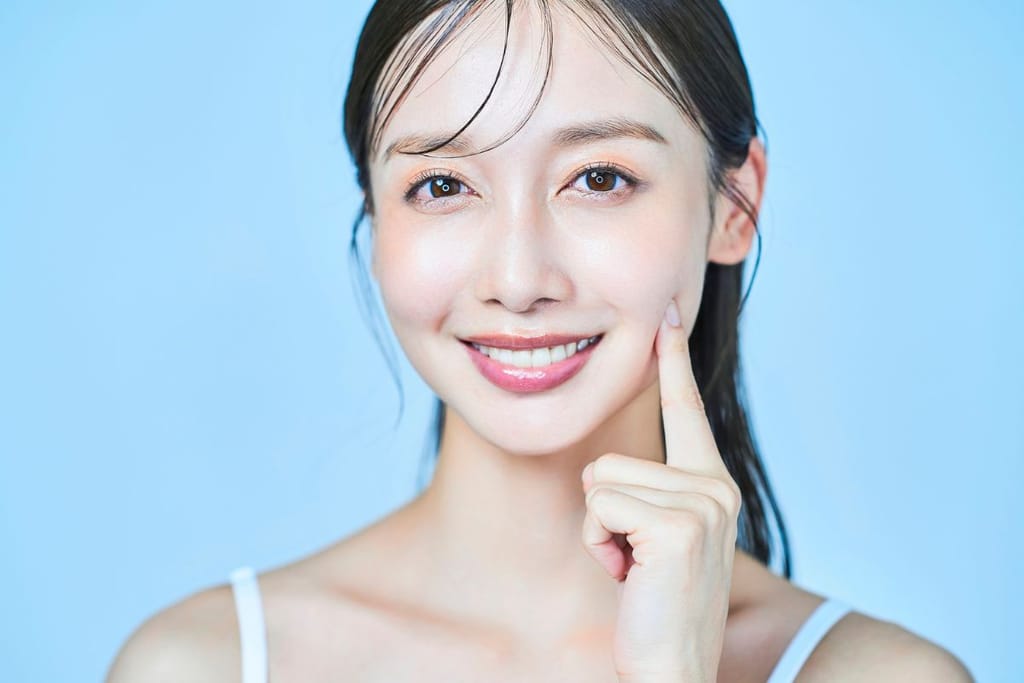 Japanilainen nainen sinistä taustaa vasten. Studiokuva naisesta, jolla on hyvä iho, terveet hiukset ja japanilaiset kauneusihanteet täyttävä ulkomuoto. Kuvituskuva mutta voisi toimia myös mainoksena. 