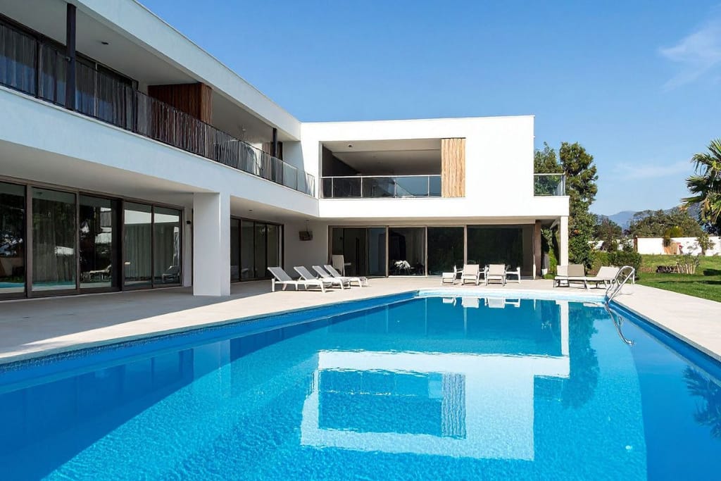 iso sinivetinen uima-allas, muutama aurinkotuoli ja lasiset kaiteet amerikkalaisessa luksustalossa