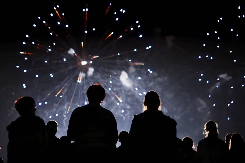 Ihmisten siluetit jotka katsovat ilotulitusta. Kuvituskuva uusivuosiahdistusartikkelille. 