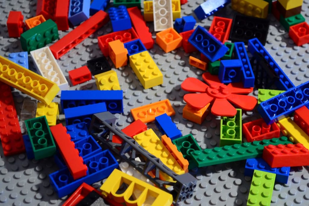 Legopalikoita legomatolla, joilla rakennetaan jotain teknisempiä kokonaisuuksia. Litteitä värikkäitä palikoita. 