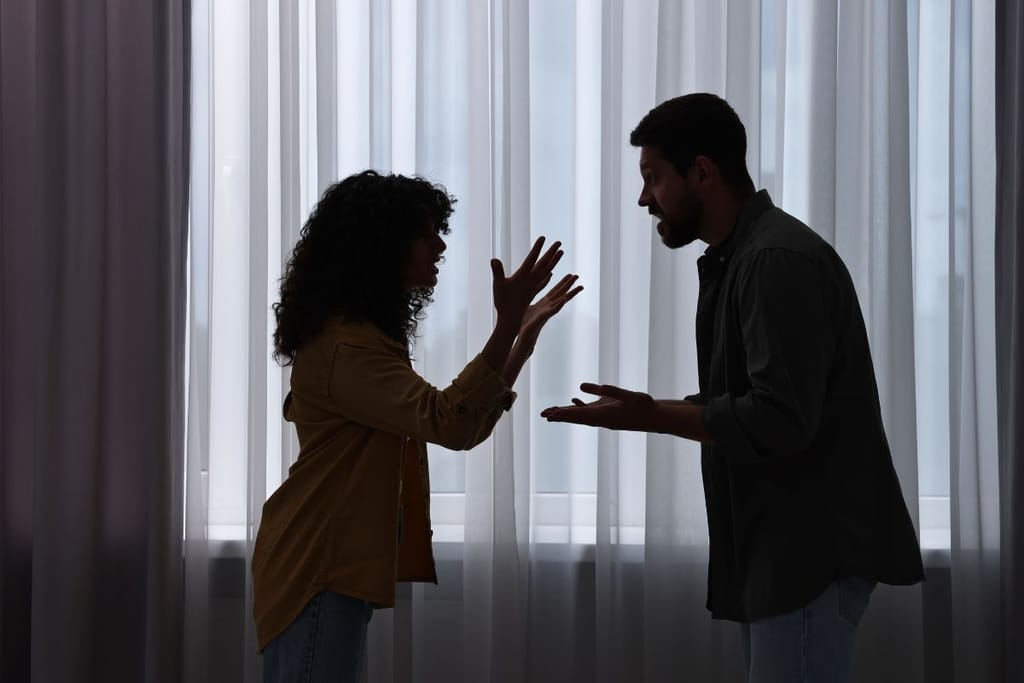 Pariskunta riitelee valkean verhon edessä että heistä näkyy vain siluetit. 