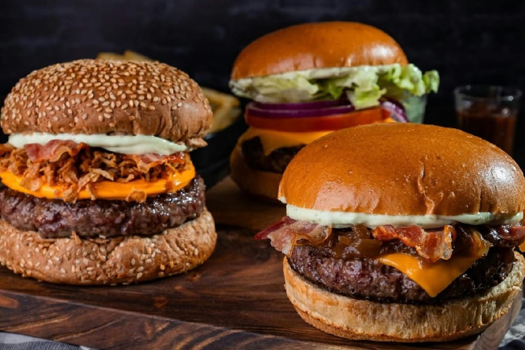 Steakhouse-nurgereita, burgereita joiden välissä paksut pihvit ja paljon erilaisia täytteitä pöydällä.