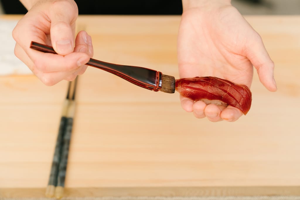 Hanayagi Omakase -ravintolassa sivellään sushia siveltimellä. 