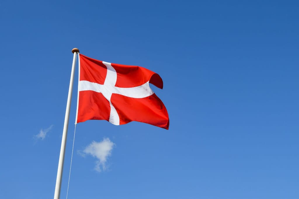 Tanskan lippu sinistä taivasta vasten hulmuaa tuulessa.
