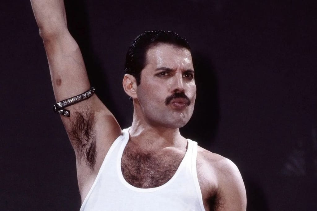 Freddie Mercury esiintyy Queen-yhtyeen konsertissa valkoisessa hihattomassa paidassa käsi kohotettuna lavalla.