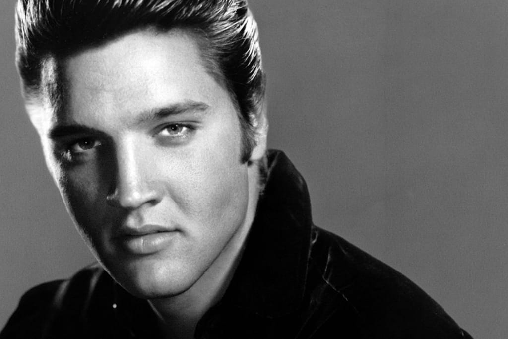 Mustavalkoinen studiokuva Elviksestä, jossa hän on uransa nousuvaiheessa. Hän katsoo kameraan määrätietoisella katseella. 