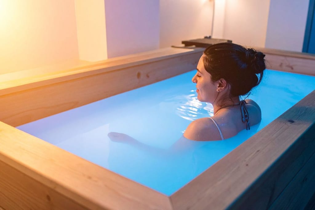 Henkilö istuu kylmävesialtaassa sisätiloissa, vesi on sinertävää ja valaistus pehmeä.