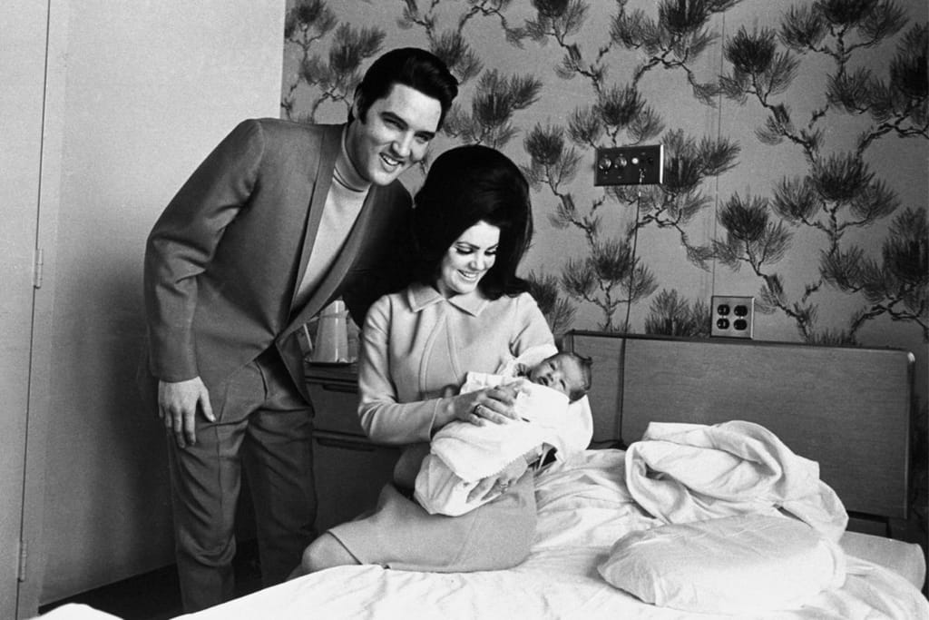 Kuvassa Elvis Presley vaimonsa Pricillan ja vastasyntyneen tyttärensä Lisa Marien kanssa. Mustavalkoinen otos Lisa Marien syntymävuodelta.