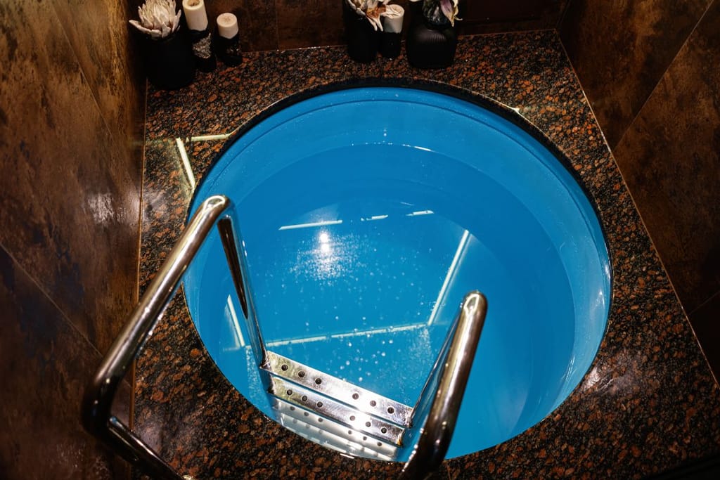 Ylhäältä kuvattu pyöreä kylmävesiallas, jossa on metalliset tikkaat ja sininen vesi.