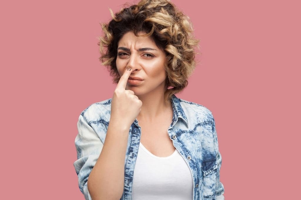 Nainen koskettaa nenäänsä ja katsoo kameraa epäilevä ilme kasvoillaan.