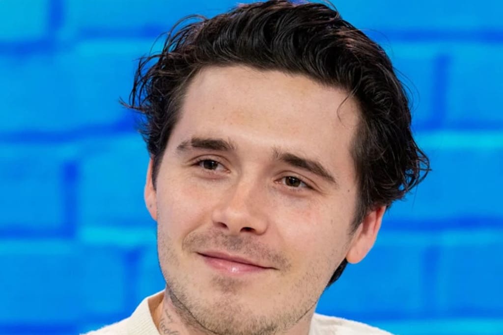 Tummahiuksinen nuorukaisen kasvot sinistä tiiliseinää vasten. 