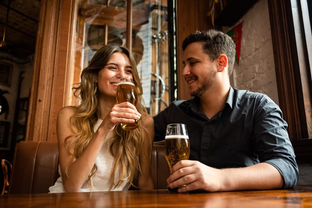 Nainen ja mies istuvat baariympäristössä oluella. Mies katsoo naista ja nainen katselee jonnekin kaukaisuuteen.