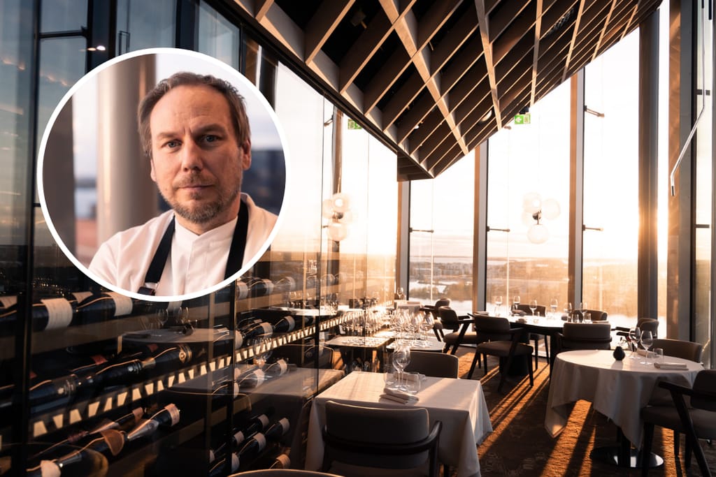 Ravintolasali suurine ikkunoineen ja viinikaappeineen, etualalla kokin muotokuva.