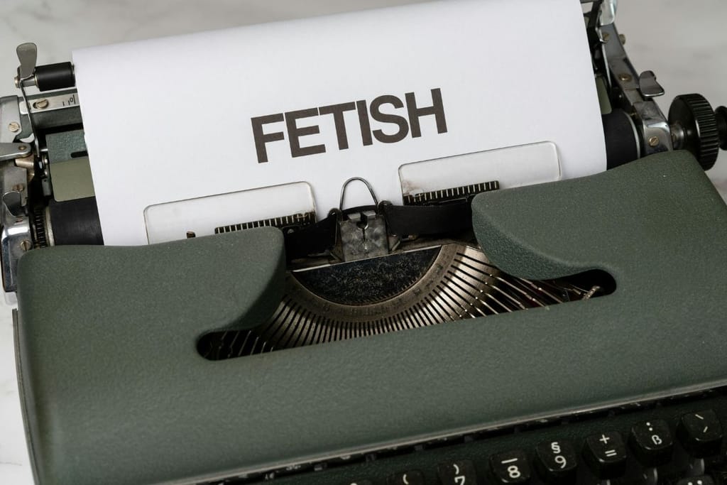 Vanhanaikainen kirjoituskone, jossa on A4:n paperi. Paperiin on kirjoitettu "FETISH" isoilla kirjaimilla.