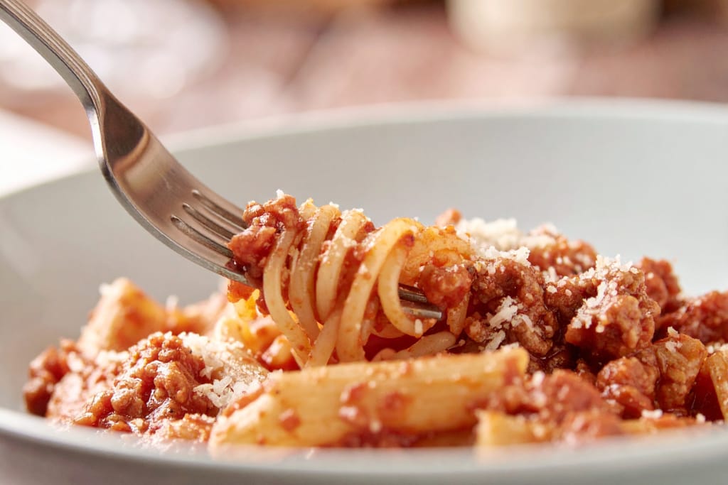 Spagettia ja bolognesekastiketta pyöritellään haarukkaan.