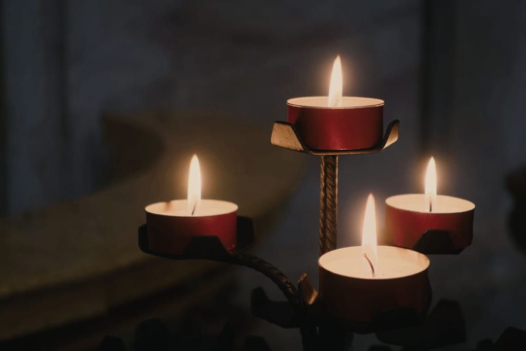 Tuikkukynttilöitä palaa pimeässä monitasoisella kynttilänjalalla.