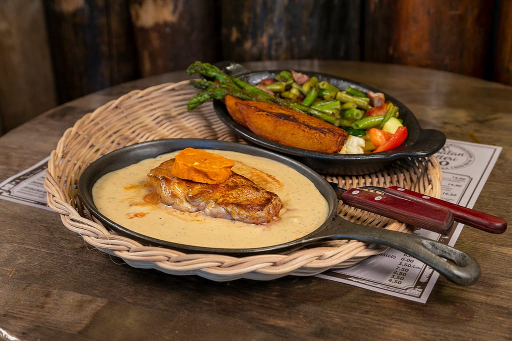 Paistettu pihvi kastikkeessa pannulla, lisukkeena vihanneksia ja paahdettu bataatti.