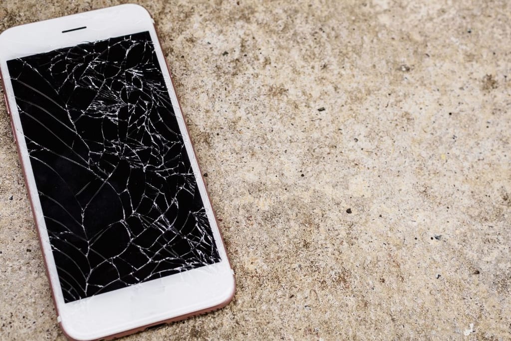 Rikkinäinen älypuhelin, joka on betonilla. 