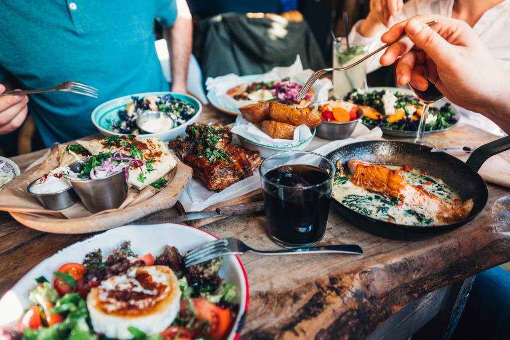 Ihmiset jakavat erilaisia ravintola-annoksia pöydän ääressä